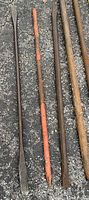 Group of five assorted iron pry/crow bars on asphalt surface showing varying lengths and shapes with rust and wear.