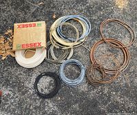 Photo showing assorted white, gray, black insulated electrical wiring coils and two coils of copper tubing in different gauges.