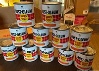Front view of eleven Rust-Oleum Stops Rust paint cans stacked in a pyramid, showing labels clearly with the brand and Stops Rust logo.