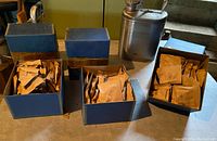 One stainless steel safety can with handle and safety cap next to three boxes with bushings inside.