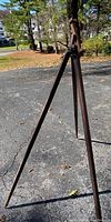 Photo showing one wooden leg and the tripod standing on asphalt outdoors