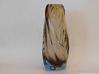 Front view of the twisted design blue base hand blown vase showing natural top rim and polished bottom.