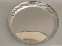 Top view of round Alessi serving tray showing reflective surface and perforated rim.