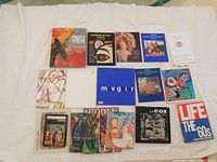Top-down image of 15 art books arranged showing colorful covers and titles related to art history, contemporary art, and sculpture, including a signed E B Cox book.