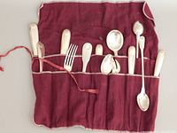 14 pieces of Christofle silver-plated flatware laid in maroon cloth holder