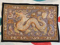 Full view of the embroidered wall hanging featuring a dragon in the center with intricate thread work and decorative borders.