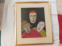 Front view of framed painting showing three stylized faces with cream mat and gold-painted frame