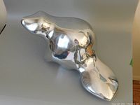 Angled view of polished metal sculpture resting on tabletop