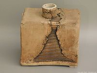 Front view of square modernist pottery vase showing textured crackle surface and grooved triangular pattern with cylindrical neck