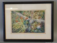 Framed oil crayon painting visible through glass showing garden foliage with red and white flowers and a fence.