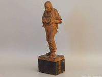 Three-quarter view of full carved figure on square base