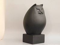 Front three-quarter view of matte black cat sculpture on base
