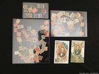 Three transparent sheets containing various loose United States and Germany stamps along with two Abraham Lincoln post cards placed beside them.