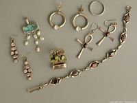 Full lot including bracelet with garnets, various earrings including pearl and abalone shell design, silver ring, and decorative pendant.