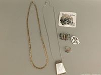 All jewelry items laid out on a flat surface including necklaces, brooches, and rings