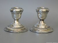 Front view of two sterling silver candle holders showing full height and base detail.