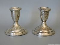 Front view of the pair of sterling silver candle holders placed side by side showing their design and condition.