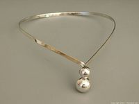 Sterling silver modernist necklace with tapered band and dual spheres on clasp, shown from front angle.