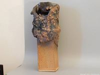 Front view of tall Brutalist style art pottery vase showing textured dark upper and smooth rectangular base.