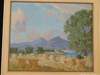 Full view of framed oil painting showing field stooks, water and mountains under sky