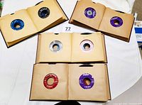 Four albums containing fifty 45 RPM records, each in individual sleeves with visible record labels from Decca, Capitol, RCA Victor, and Columbia.