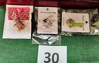 Three animal pins in original packaging showing colorful details of penguin, dog, and wasp pins.