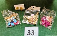 Photo showing all jewelry pieces in original plastic packaging: three necklaces and one pair of earrings. The earrings are on a branded Betsey Johnson card.