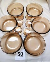 Top view of six amber glass bowls with handles, arranged in a circle showing inside and rim detail.