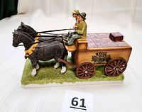 Side angle photo showing two horses harnessed to grape wine cart with driver figures. One rein is detached.