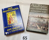 Photo showing front covers of both hardcover books: 'Our Pennsylvania' with blue cover and historic building illustration, and 'Philadelphia Holy Experiment' with illustrated city scene dust jacket.