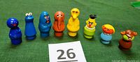 Front view of all eight Sesame Street Little People figures arranged in a line showing full front details and colors.