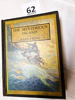Front cover of The Mysterious Island by Jules Verne showing an illustrated image of a balloon flying over water.