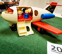 Side view of vintage Fisher Price airplane showing the open cabin with four colorful plastic figures seated and the boarding stairs.