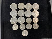 Top side view of 18 Kennedy half dollar coins arranged on black velvet.