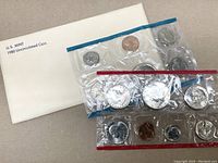 Photo of the two uncirculated coin sets sealed in plastic sleeves accompanied by original 1980 US Mint envelope.