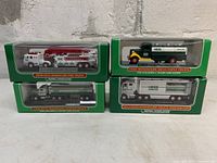 Front view of boxed 2010, 2008, 1998, and 2013 Hess miniature trucks aligned in two stacks