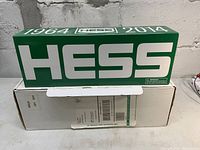 Green Hess collector's box with 1964 and 2014 printed on top, showing the Hess logo and side image of a truck, placed on top of a white shipping box with labels.