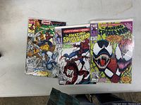 Photo of three comic books sleeved on a light gray table, showing covers of Amazing Spider-Man #360, #361, and #363