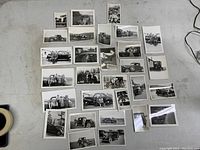 All 29 black and white vintage automotive photos spread out on a flat surface. Various sizes visible with edges showing slight curves.