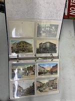 Photo of album open to pages showing six postcards each, various Gloucester street and building scenes in color and black and white.