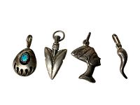 Four sterling silver charms photographed on white background for clear view of details and size comparison with ruler.