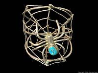 Front angle of large cuff bracelet showing spider web wire design and turquoise detailed spider center.