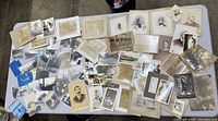 Photo showing the entire collection spread out on a table, includes many black and white and sepia toned photographs of various sizes with portraits and group scenes.
