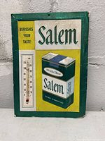 Front side of metal advertising sign for Salem cigarettes showing cigarette pack graphic and thermometer.