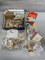 Overview of shoebox with loose and bagged postage stamps, stamp booklets and envelopes