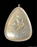 Front side of the sterling silver floral ornament showing the embossed flower design and hanging loop