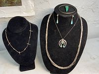 Front view of jewelry on black displays showing necklaces with turquoise, earrings, ring, and bracelet