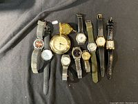 Overview photo showing all eleven watches and clock laid out on a dark surface.