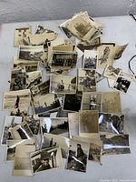 Overview of many black and white photos scattered on a table showing soldiers, buildings, and various scenes.