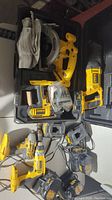 Yellow and black DeWalt power tools array including drill, circular saw, reciprocating saw, impact driver, batteries and charger. Various conditions shown.